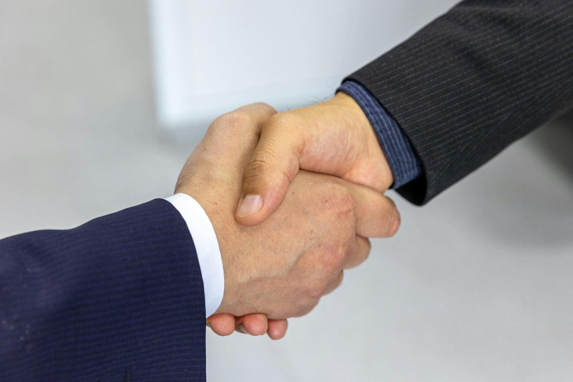 Primer plano de dos hombres de negocios dándose la mano, simbolizando acuerdo y colaboración.